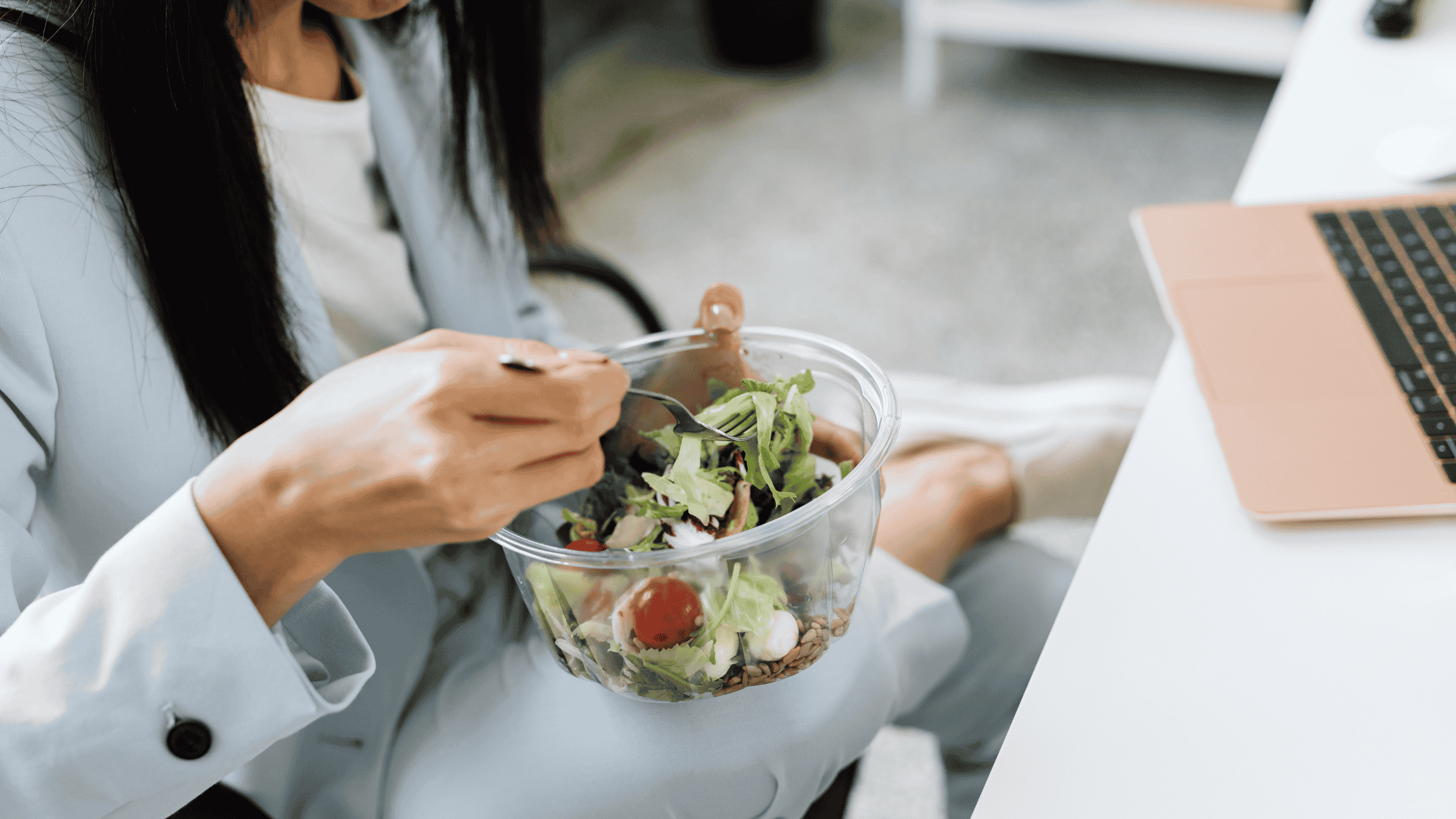 A person eating a healthy salad at their desk.