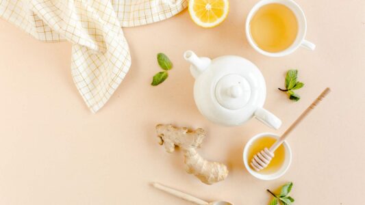 picture of white teapot and ginger beside cup of tea with health benefits of ginger