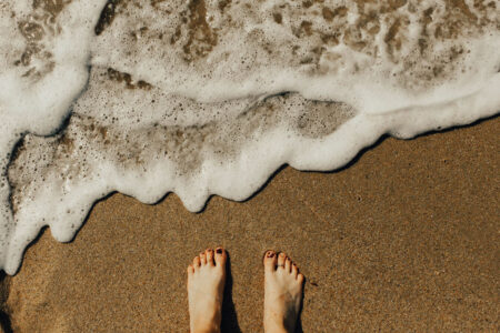 Feet on beach with surf approaching