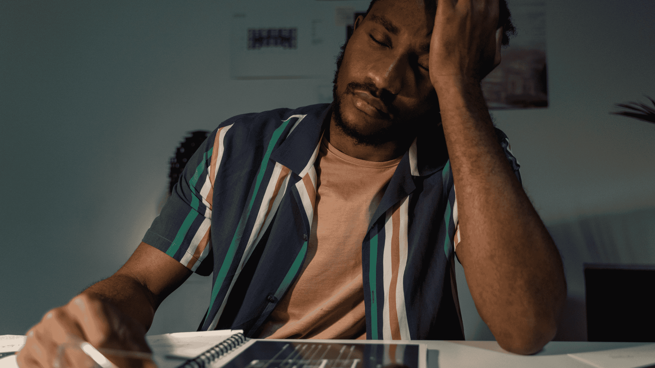 a person sitting at a desk, looking tired. Does he have a healthy liver?