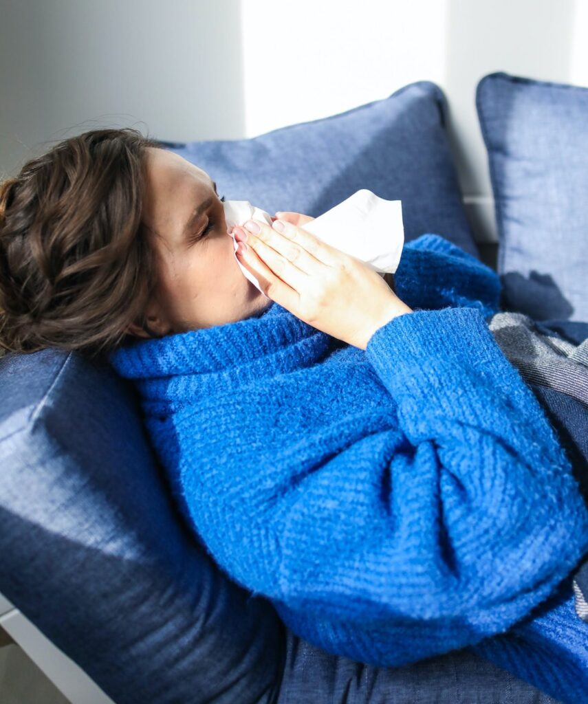 Woman in blue sweater blowing nose