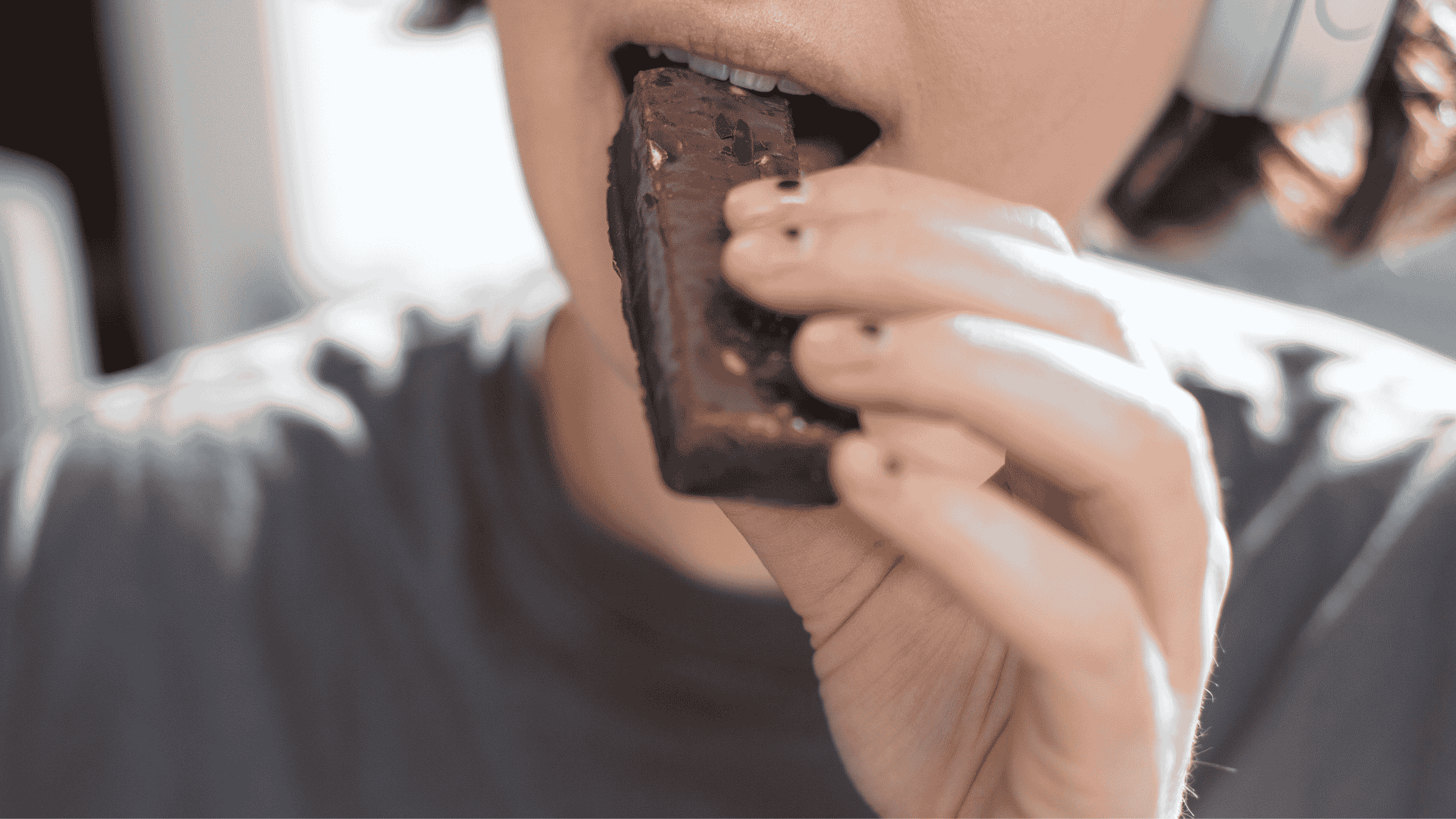 Close up of a person eating a chocolate bar. 