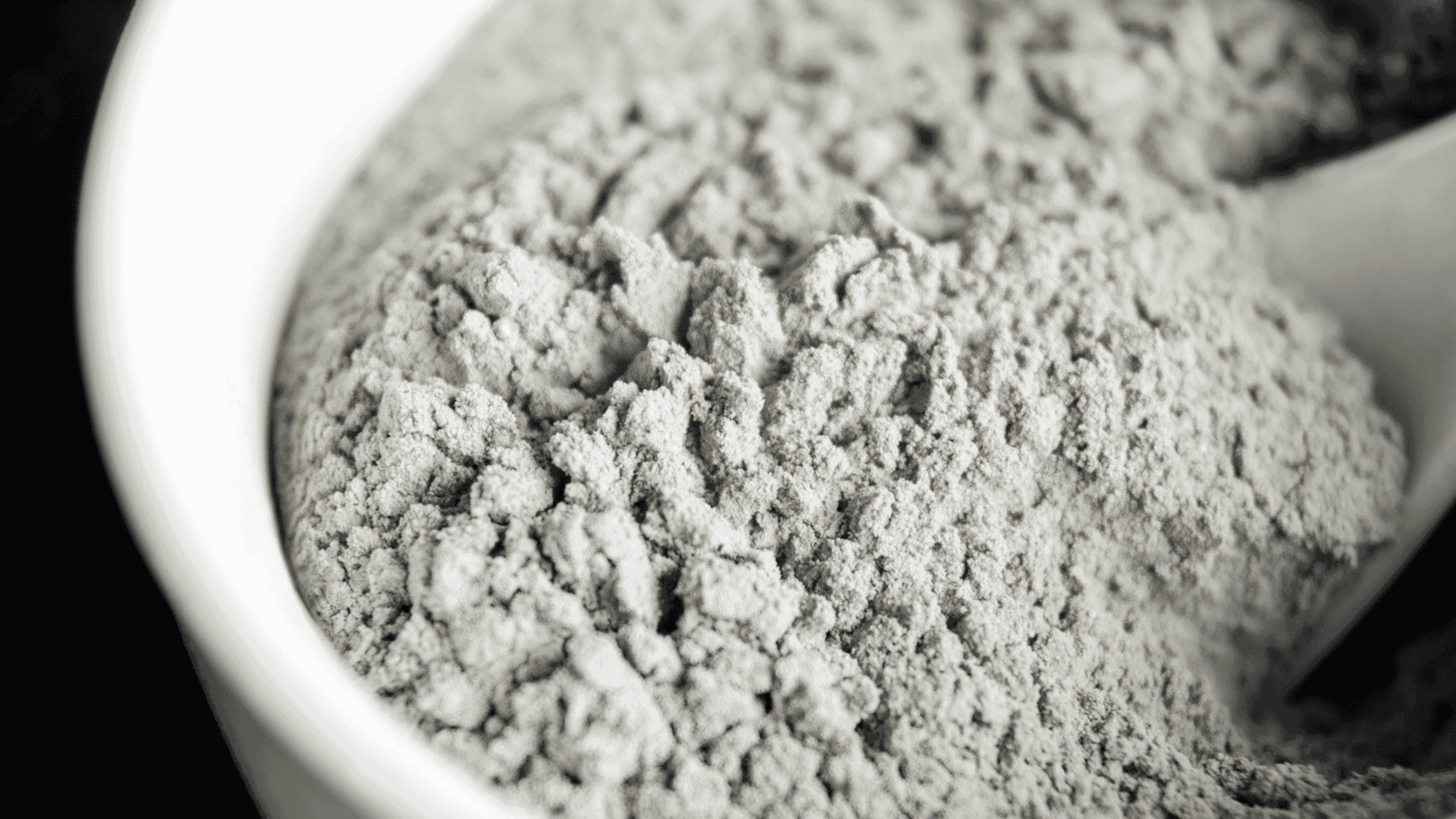 Bentonite clay powder in bowl. The many benefits of bentonite clay include detoxification and skin care