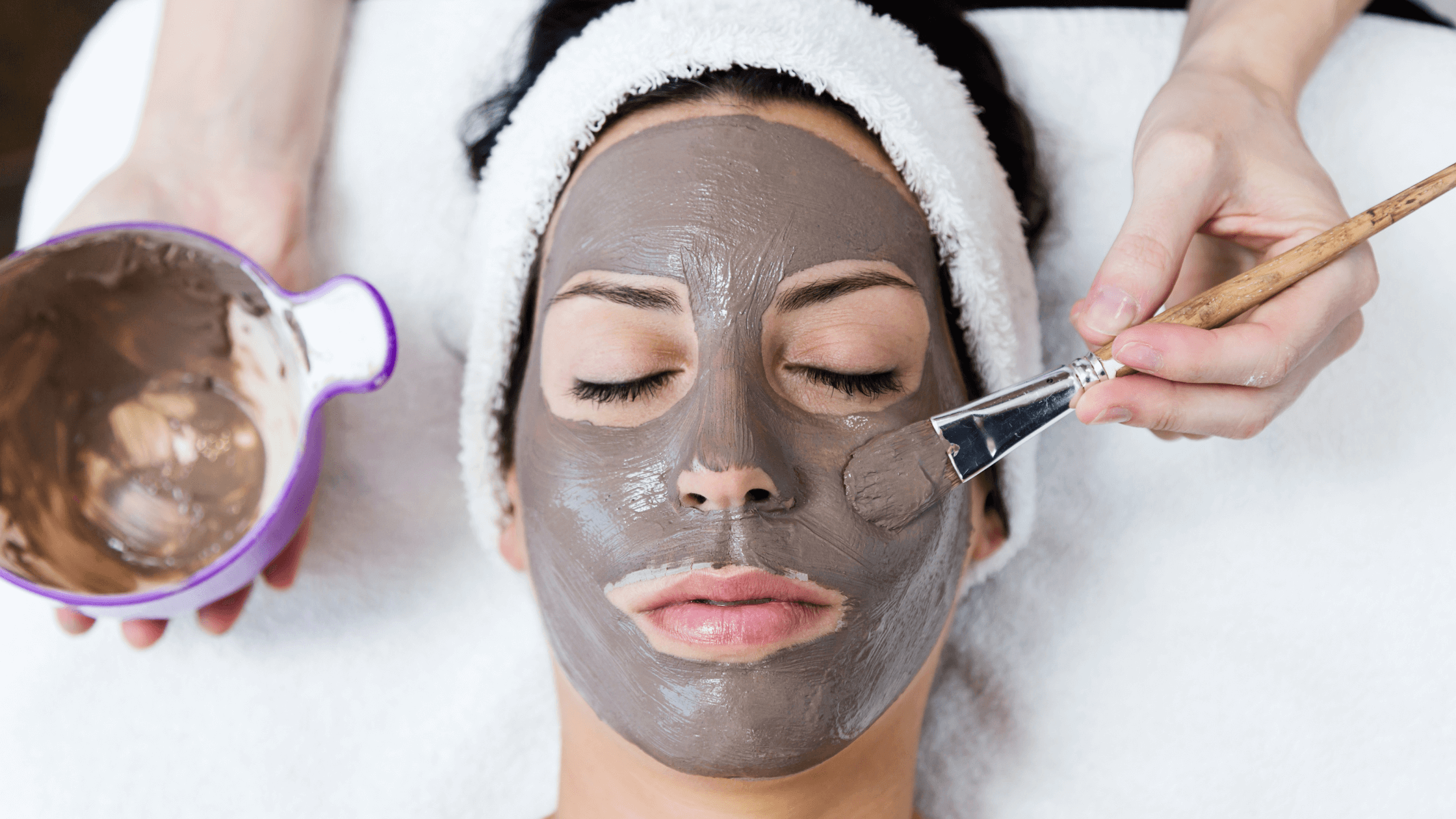 close up of a woman with dark bentonite clay face mask.
