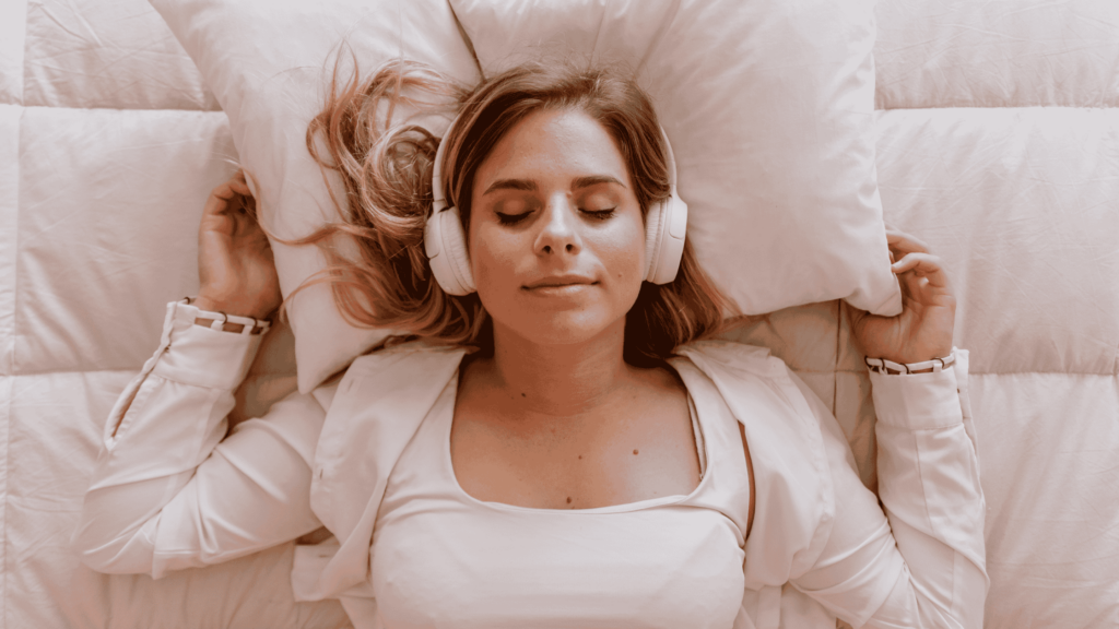 Women wearing headphones learning how to begin meditation while laying in bed. 