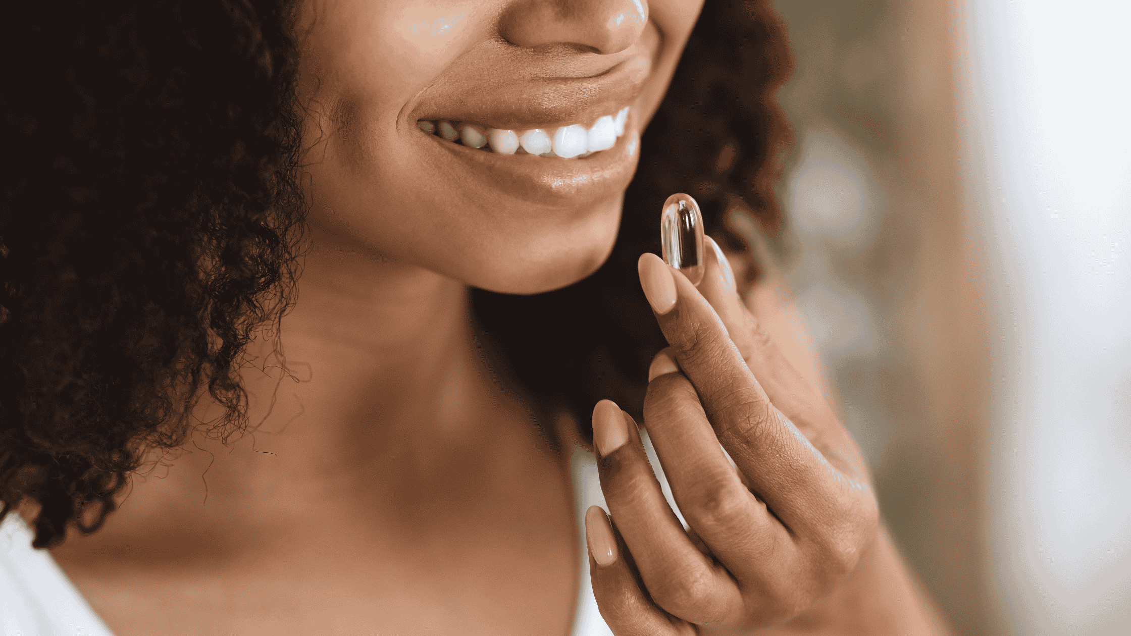 A black woman is putting a supplement near her mouth to ingest it. She is smiling.