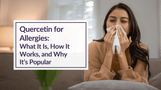 A woman wearing a brown sweater is sitting on a couch. She is sneezing while covering her nose with a tissue. Text overlay reads - Quercetin for Allergies: What It Is, How It Works, and Why It’s Popular