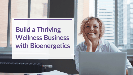 A woman with blonde hair is sitting at a desk looking over her lap top and smiling. Overlay Text: Build a Thriving Wellness Business with Bioenergetics