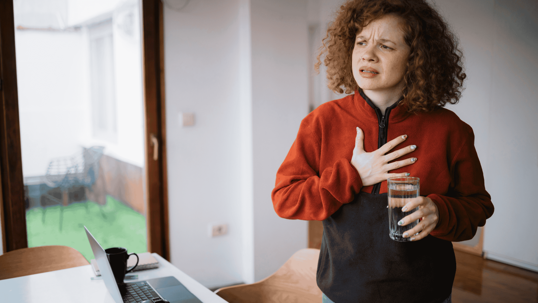 Woman with acid reflux with a glass of water in hand.