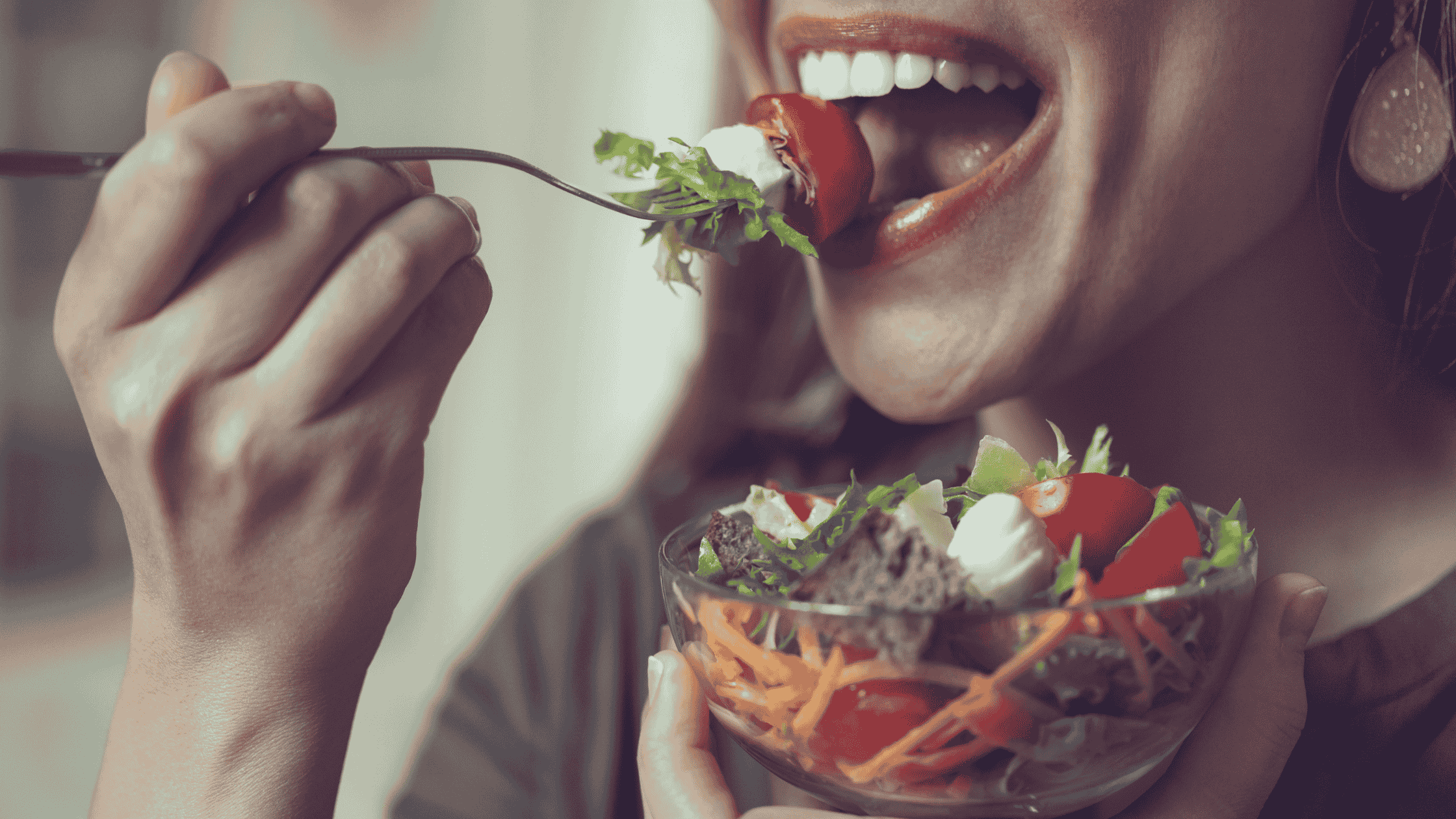 a close up of a mouth eating a salad.